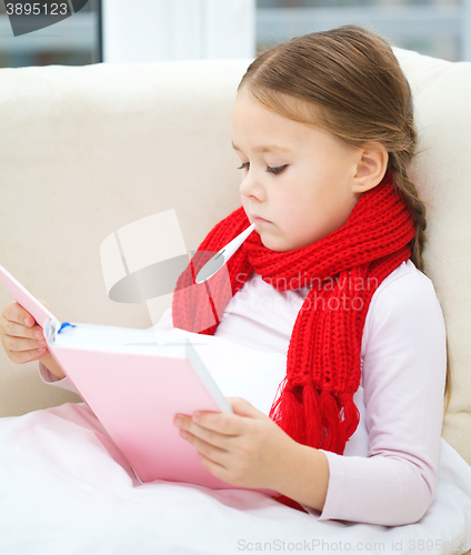 Image of Ill little girl with thermometer is reading book
