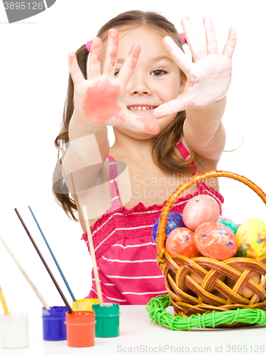 Image of Little girl is painting eggs preparing for Easter
