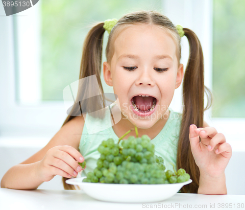 Image of Cute little girl is eating green grapes