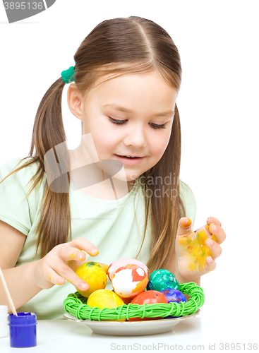 Image of Little girl is painting eggs preparing for Easter