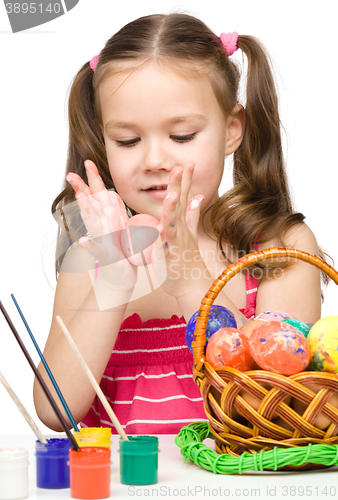 Image of Little girl is painting eggs preparing for Easter