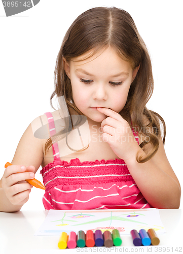 Image of Little girl is drawing using colorful crayons