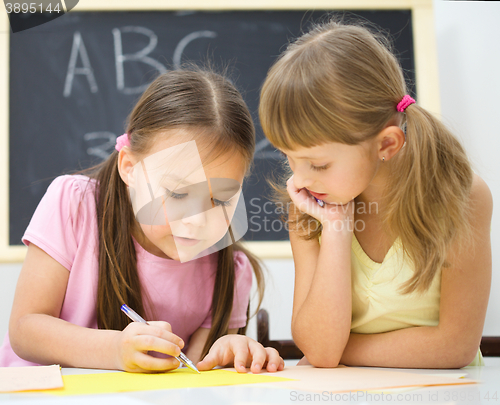 Image of Little girls are writing using a pen