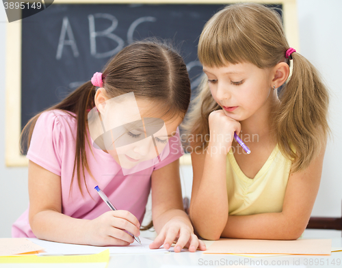 Image of Little girl is writing using a pen