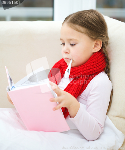 Image of Ill little girl with thermometer is reading book