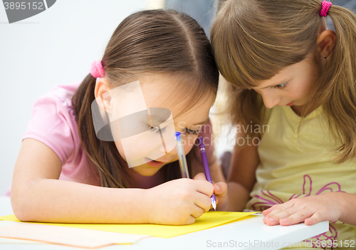 Image of Little girl is writing using a pen