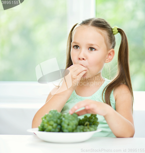 Image of Cute little girl is eating green grapes