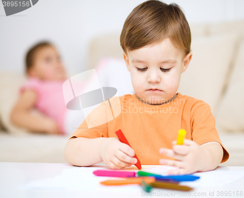 Image of Little boy is drawing on white paper