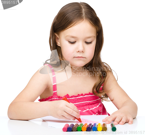 Image of Little girl is drawing using a crayon