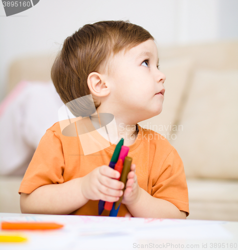 Image of Little boy is drawing on white paper