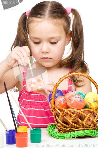 Image of Little girl is painting eggs preparing for Easter