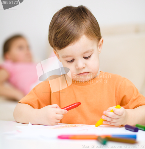 Image of Little boy is drawing on white paper