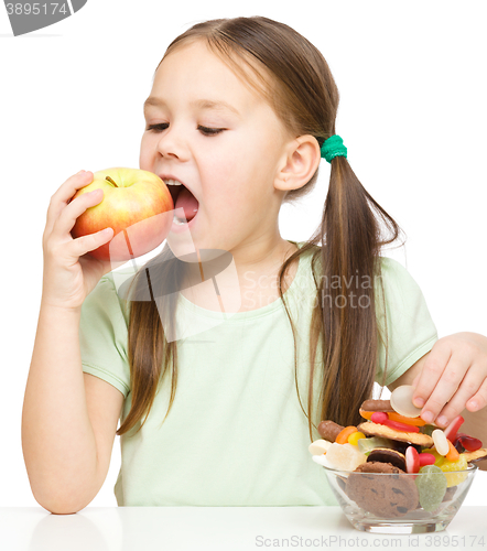 Image of Little girl choosing between apples and sweets