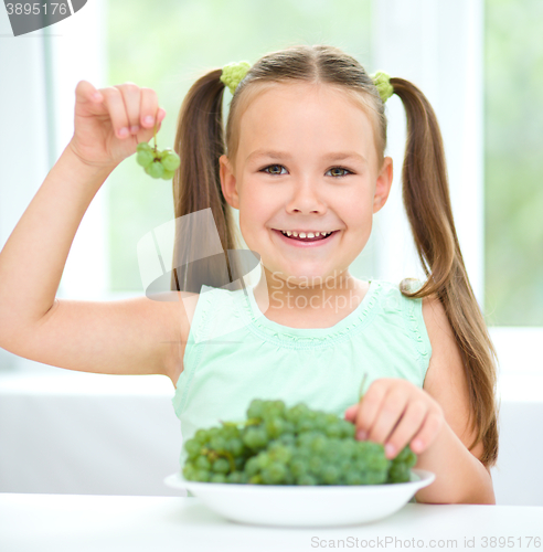 Image of Cute little girl is eating green grapes