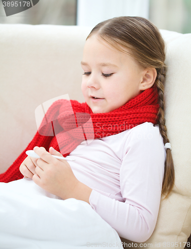 Image of Ill little girl is reading thermometer