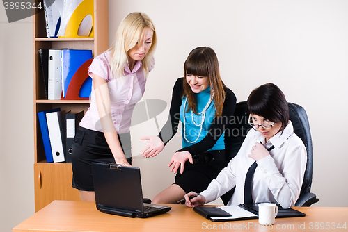 Image of Three businesswomen at office working with laptop