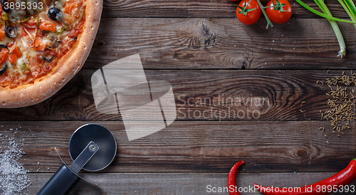 Image of Tasty pizza with ingridients on a wooden board.