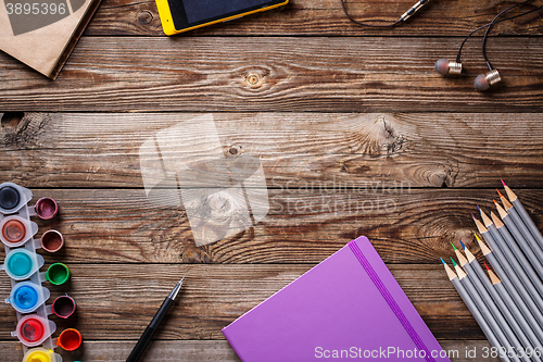 Image of Watercolors, color pencils and sketchbook on wooden table. Flat lay photo with empty space for logo, text.