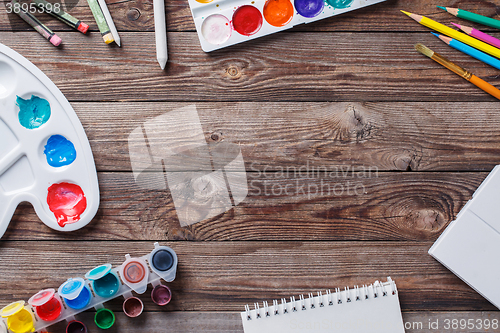 Image of Paper, watercolors, paint brush and some art stuff on wooden   table