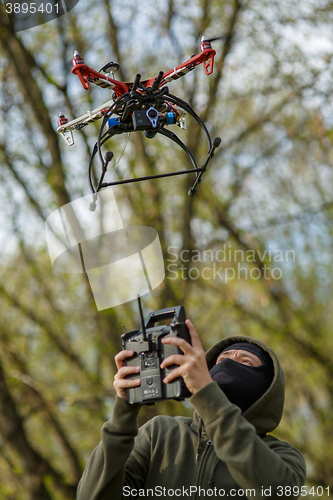 Image of Man in mask operating a drone with remote control.