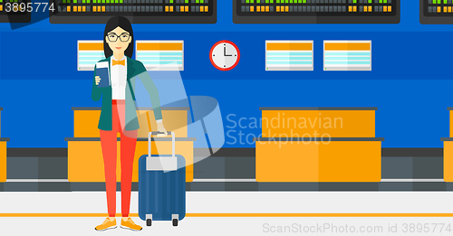 Image of Woman standing with suitcase and holding ticket.