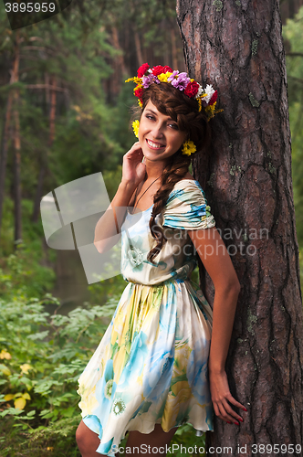 Image of Attractive woman with flower wreath near pine