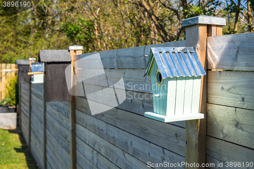 Image of Bird houses on a row at a fence