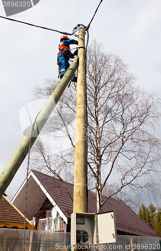 Image of Electrician connects wires on a pole in a country house