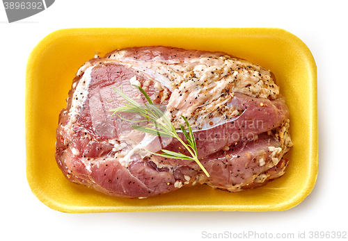 Image of raw marinated pork tenderloin in plastic try