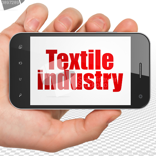 Image of Industry concept: Hand Holding Smartphone with Textile Industry on display