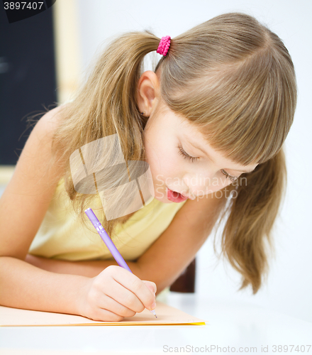 Image of Little girl is writing using a pen