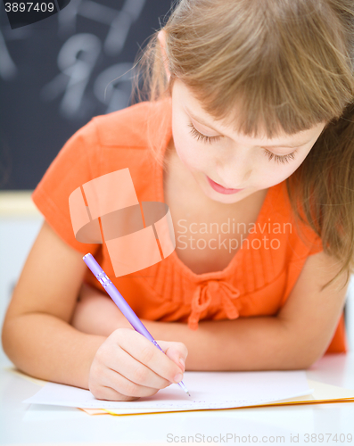 Image of Little girl is writing using a pen