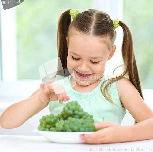 Image of Cute little girl is eating green grapes