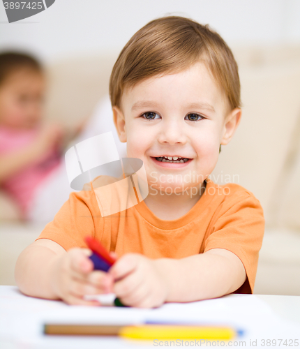 Image of Little boy is drawing on white paper