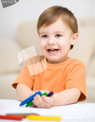 Image of Little boy is drawing on white paper