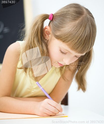 Image of Little girl is writing using a pen