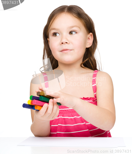 Image of Little girl is drawing using colorful crayons