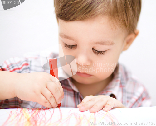 Image of Little boy is drawing on white paper