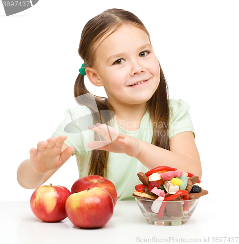 Image of Little girl choosing between apples and sweets