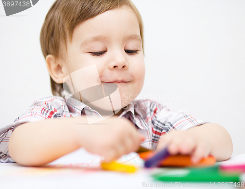 Image of Little boy is drawing on white paper