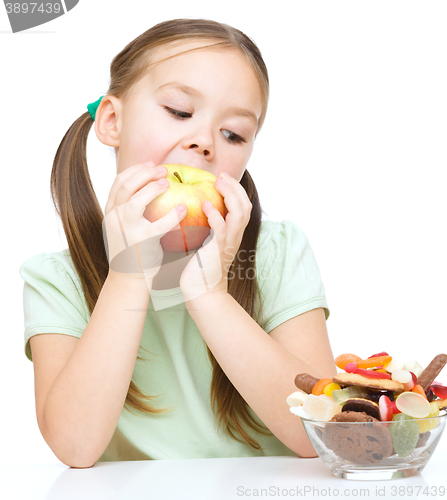 Image of Little girl choosing between apples and sweets