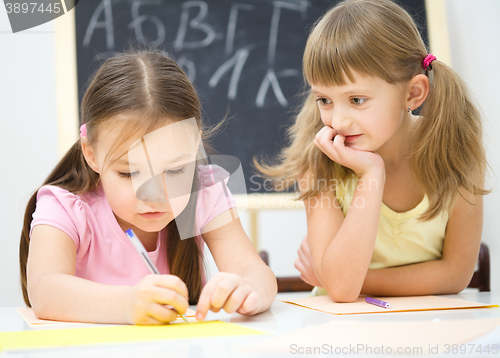 Image of Little girls are writing using a pen