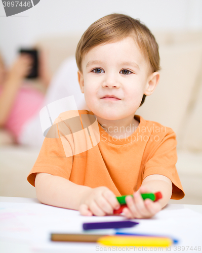 Image of Little boy is drawing on white paper