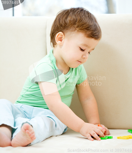 Image of Boy is playing while sitting on couch