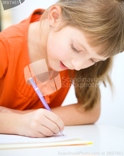 Image of Little girl is writing using a pen