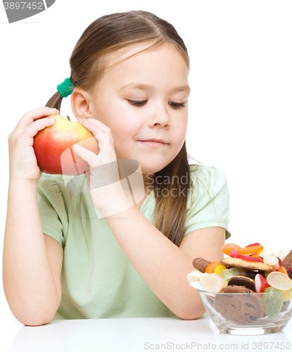 Image of Little girl choosing between apples and sweets