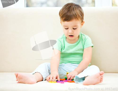 Image of Boy is playing while sitting on couch