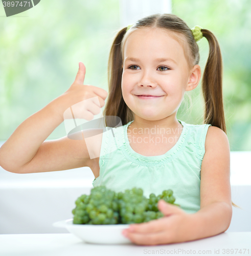 Image of Cute little girl is eating green grapes