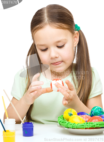Image of Little girl is painting eggs preparing for Easter