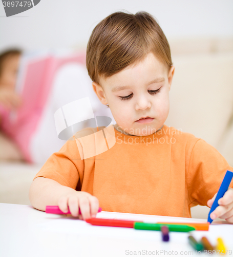 Image of Little boy is drawing on white paper